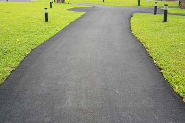 New asphalt which is a smooth road walkway in the green grass garden.