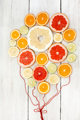 Fresh bright juicy citrus sliced and collected together with red ropes as balloons. In white wood background. lemon, orange, lime, grapefruit, sweetie, pomelo, oroblanco