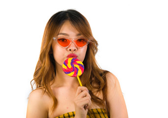portrait of young happy and sexy Asian Korean girl in cool fashion sunglasses eating lollipop candy...