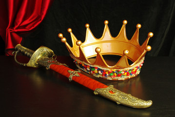 Crown, sheathed sword and drapery. Isolated on black