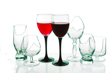 Two glasses of red wine on the background of broken glasses on a light background