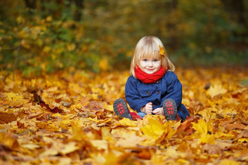 Little autumn funny girl sitting in autumn park. Selective focus, copy space.