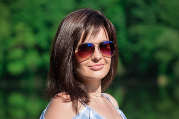 Close up portrait of young woman dressed on checkered pattern dress. Forest and lake background.