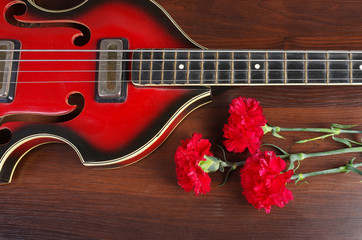 Electric guitar and red carnations on a wooden table