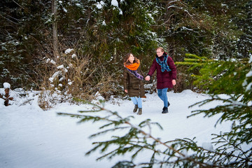 Young cute couple at a winter forest. Fun and joy concept