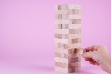 Hand taking one block on the tower. Business and construction concept.