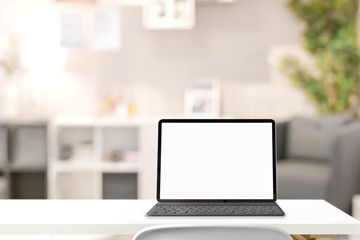 Mockup blank screen tablet with smart keyboard on table over living room background