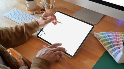 Cropped shot of designer using graphics tablet while working with computer at studio or office
