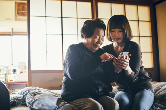 Senior and young woman using smartphone together