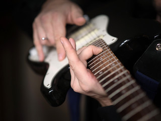Fototapeta premium Male hands playing on electric guitar, close up, selected focus