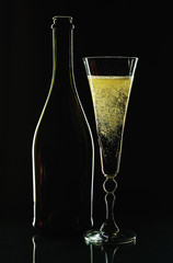 Glass of champagne and bottle on a black background