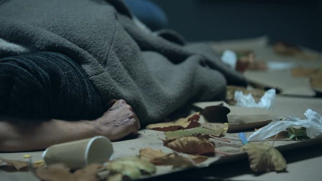 Drug addicted homeless person sleeping on urban street after taking dose, abuse