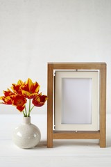  floral frame.Flower card.  empty frame and red tulips in a vase on white wooden background.Mothers Day. International Women's Day. copy space.