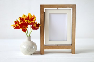  floral frame.Flower card. Wooden  frame and red tulips in a vase on white wooden background.Mothers Day. International Women's Day. copy space.