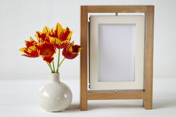  floral frame.Flower card. Wooden empty frame and red tulips in a vase on white wooden background.Mothers Day. International Women's Day. copy space.