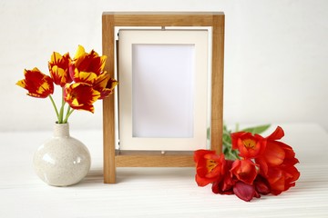  floral frame.Flower card. Wooden empty frame and red tulips  on white wooden background.Mothers Day. International Women's Day. copy space.