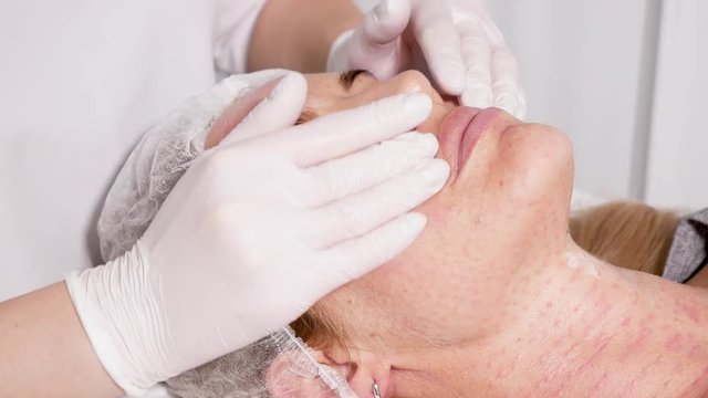 doctor beautician pricks the patient's face with a drug based on hyaluronic acid to tone the skin of a woman