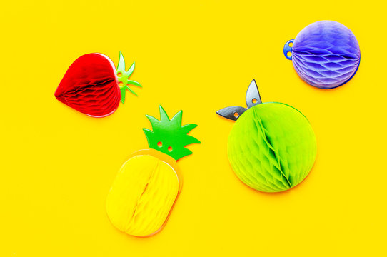 Flat lay bright tropical fruits of paper, strawberry, pineapple, apple, plum on yellow background top view copy space. Minimalistic creative summer food concept, origami paper fruit