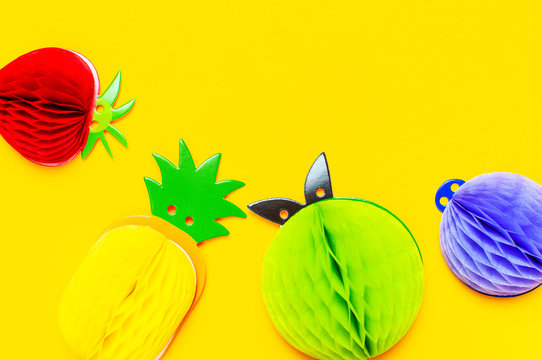 Flat lay bright tropical fruits of paper, strawberry, pineapple, apple, plum on yellow background top view copy space. Minimalistic creative summer food concept, origami paper fruit