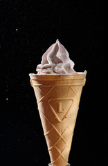 Beautiful and appetizing meringue ice-cream cake. On a black background with side light. Sugar powder in flight.