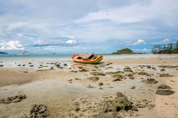Old and broken wooden boat stranded on the sandy beach in Koh Samui island, Thailand