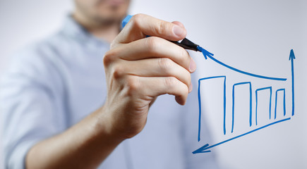 Male hand drawing a graph using a blue marker