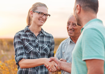 Naklejka premium Handshake for deal, group of farmers standing in a field examining soybean crop before harvesting.