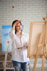 woman paints picture on canvas with oil paints in her studio