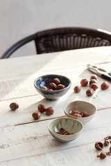 Small bowls with hazelnuts on a white wooden table in the sunlight