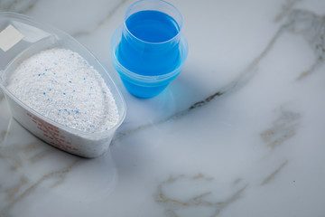 Waschmittel Pulver und blaues Flüssig Gel in Dosierung Messbecher 