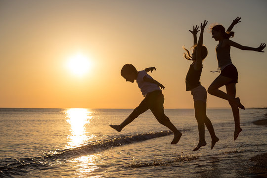 Happy children playing on the beach at the sunset time.