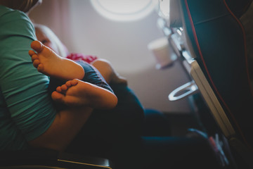 mother holding little baby on travel by plane