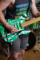 Young male guitarist playing on bright green electric guitar