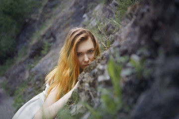 Naklejka premium A beautiful girl in a summer white dress is on the rocky slopes of the mountain . Portrait of a beautiful girl.