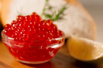 red caviar in glassware on wooden background with space for text