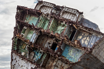Huge rusty pieces of decommissioned marine ship that was cut and left on the shore.