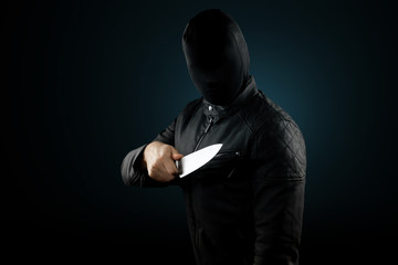 The serial killer, a maniac with a knife and a black chuolkom on his head. Halloween concept, psychopath. Copy space.