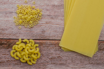 Choosing a meal of dried pasta on a wooden background.