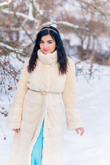Fototapeta na wymiar Arabic woman in mink fur coat and blue long romantic dress at snowy day, femininity and grace concept, winter fairytale 