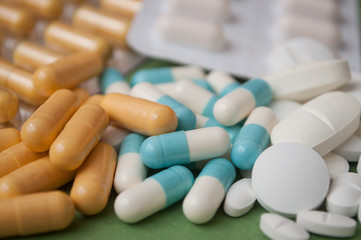 closeup of capsules, pils and drug tablets  on green background