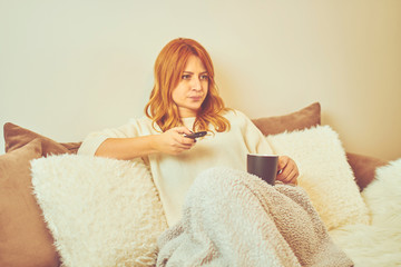 Beautiful woman drinking coffee and watching television.