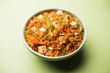 Schezwan paneer fried rice with Szechuan sauce and cottage cheese cubes. served in a bowl or plate or pan. selective focus