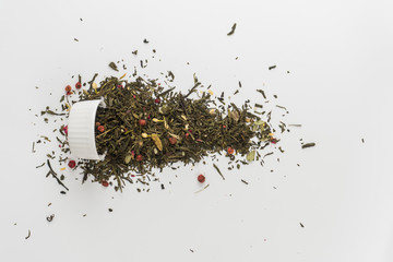 Dry leaves of Sencha green flower tea with cowberry leaf, red currant, Jasmine, rose petals, honey granules, forest berry aroma on white background