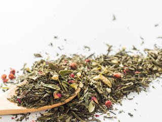 Dry leaves of Sencha green flower tea with cowberry leaf, red currant, Jasmine, rose petals, honey granules, forest berry aroma on white background