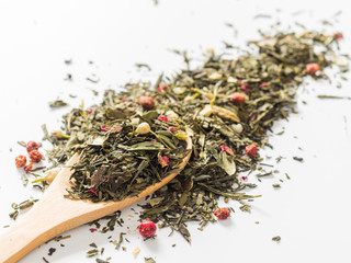 Fototapeta premium Dry leaves of Sencha green flower tea with cowberry leaf, red currant, Jasmine, rose petals, honey granules, forest berry aroma on white background