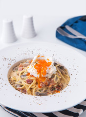 bacon  ham cheese  spaghetti carbonara topped with onsen egg on white plate in restaurant
