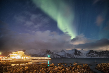 Aurora borealis on snowy mountain with light house
