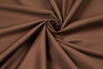 Brown sateen fabric with a shade of bitter chocolate is laid by folds on diagonal to the center in...