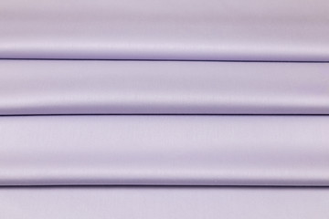 Lilac sateen fabric is laid by equal folds 