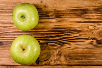 Two ripe green apples on a wooden table. Top view